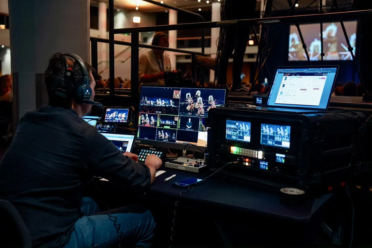 Vision operator at the switching desk wearing headphones, monitoring the programme feed